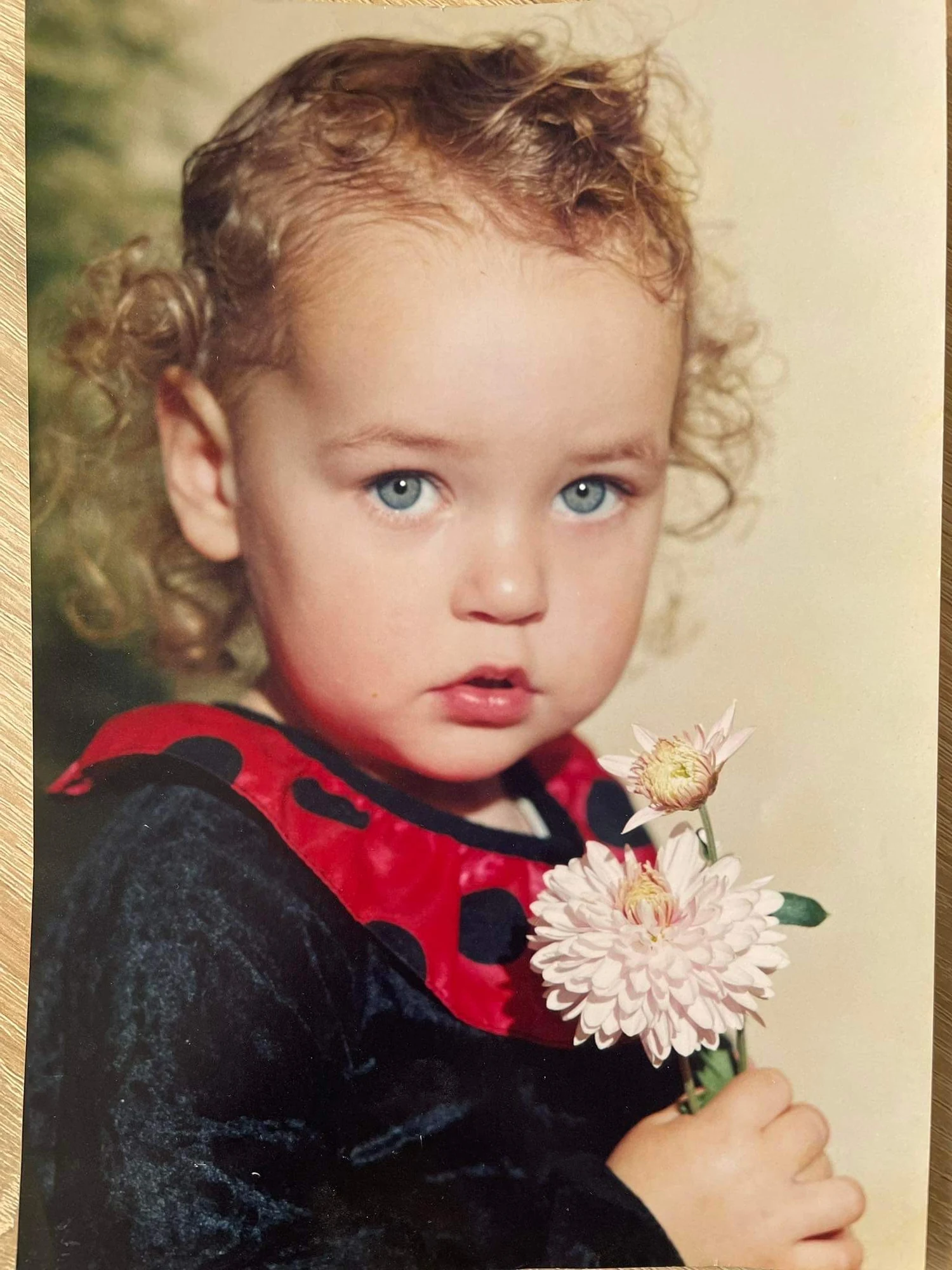 Diana als kleines Mädchen mit Locken und einer Blume